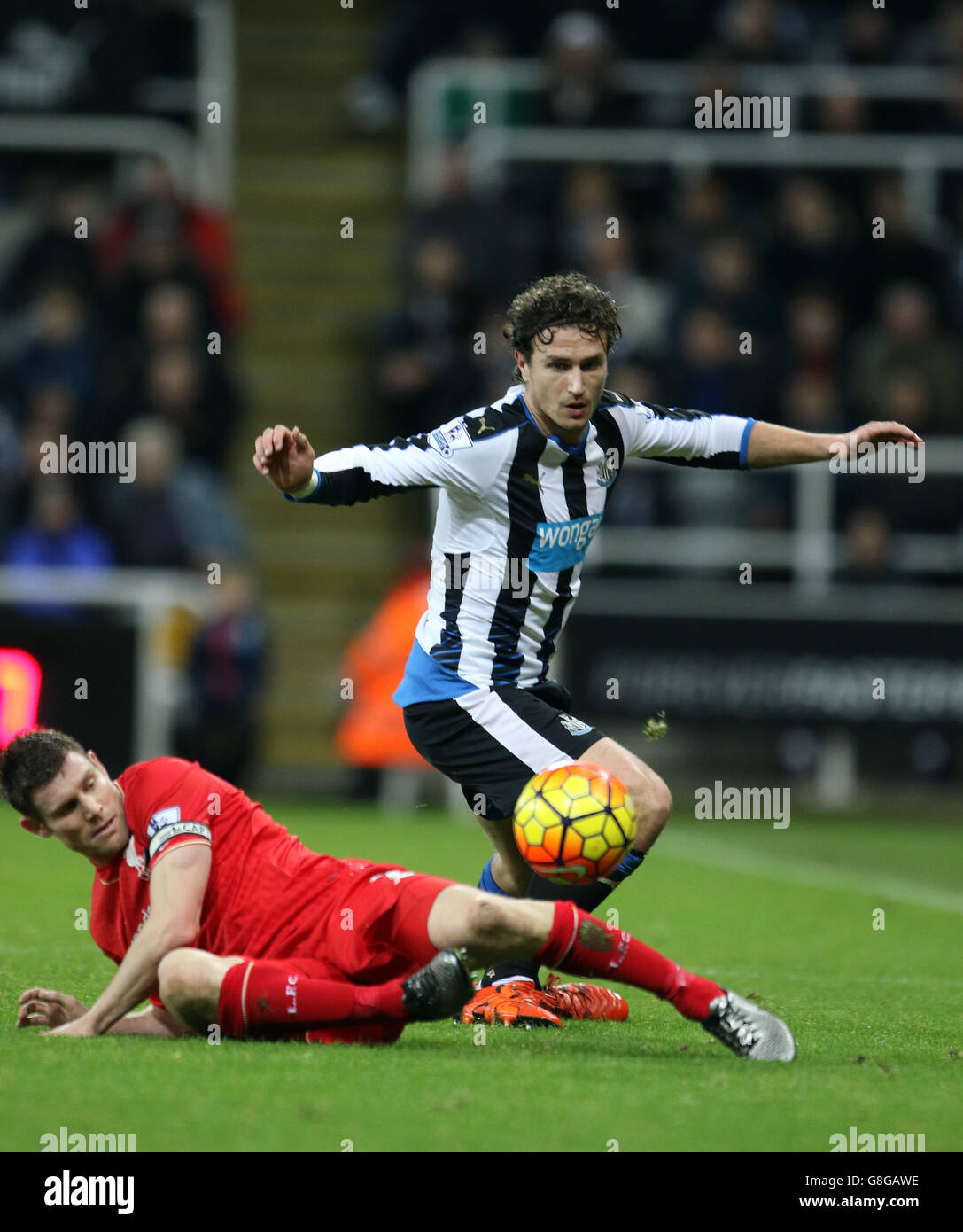Newcastle United's Daryl Janmaat is tackled by Liverpool's James Milner (left) during the Barclays Premier League match at St James' Park, Newcastle. Stock Photo
