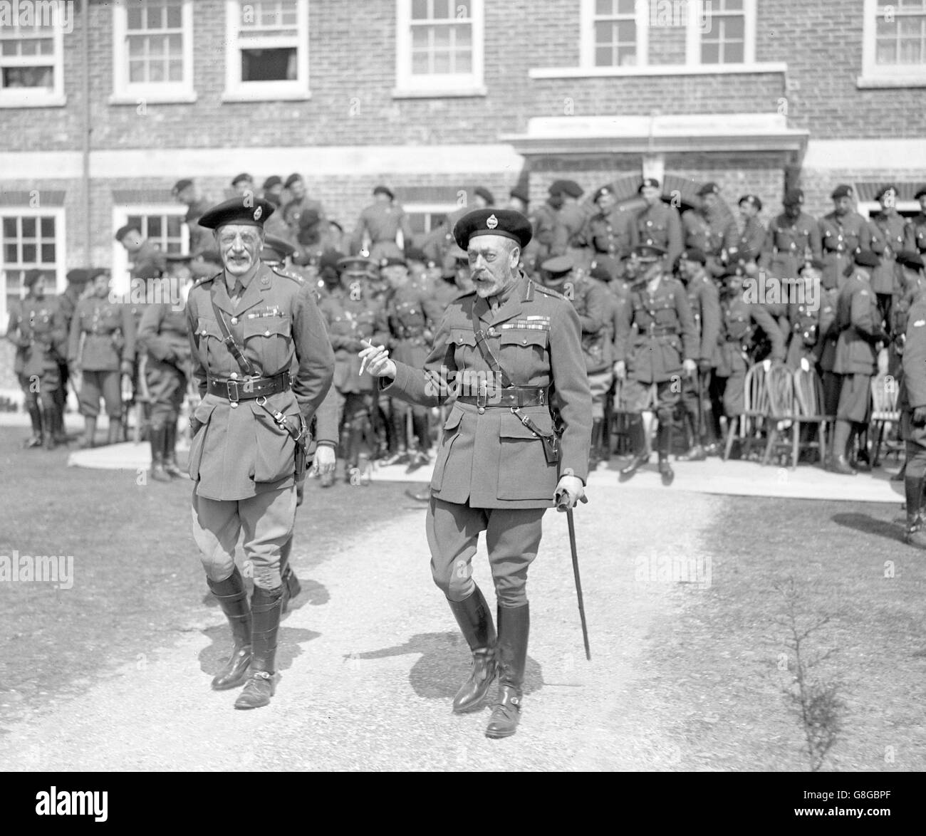 King George V leaving one of the huts after visiting members of the ...