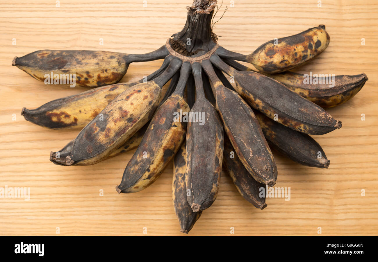 bunch of black overripe bananas on a wooden background Stock Photo