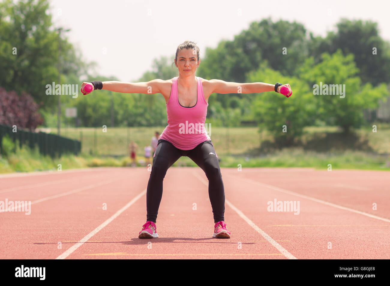 Girl athlete squat weights running track red Stock Photo