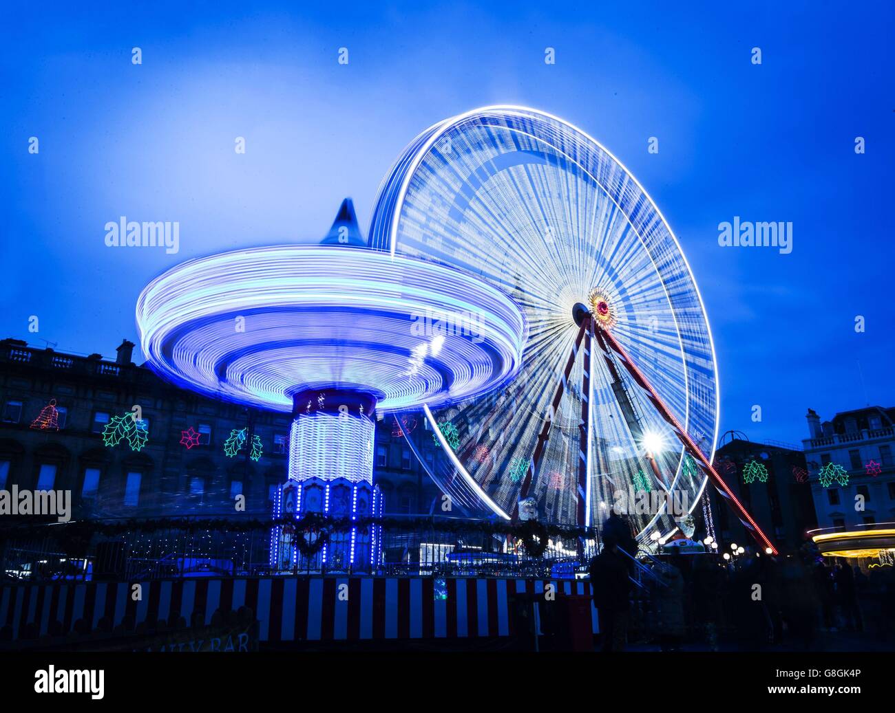 Editors please note, Long exposure photograph using tungsten white balance in daylight conditions. Fairground rides in George Square, Glasgow, as revelers enjoy the Christmas and New Year holidays. Stock Photo