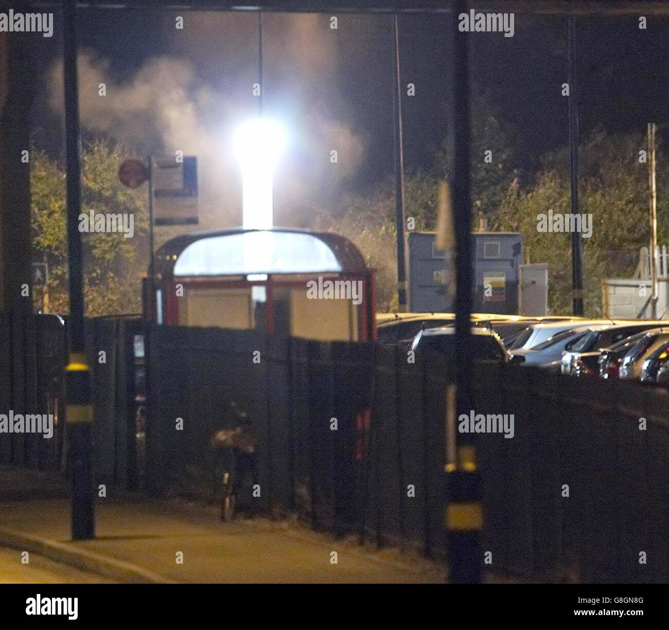Smoke drifts up under the glare of a police floodlight after a controlled explosion, in Luton Station car park where officers were examining one of two cars believed to have been hired by the London bombers. Stock Photo