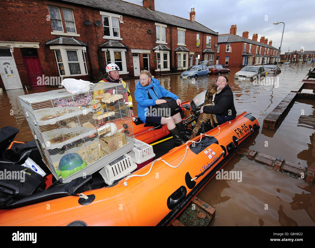 Sophie Thornton and Chris Fairclough with their dog, two cats and a chinchilla are rescued from their flooded home in Carlisle. Stock Photo