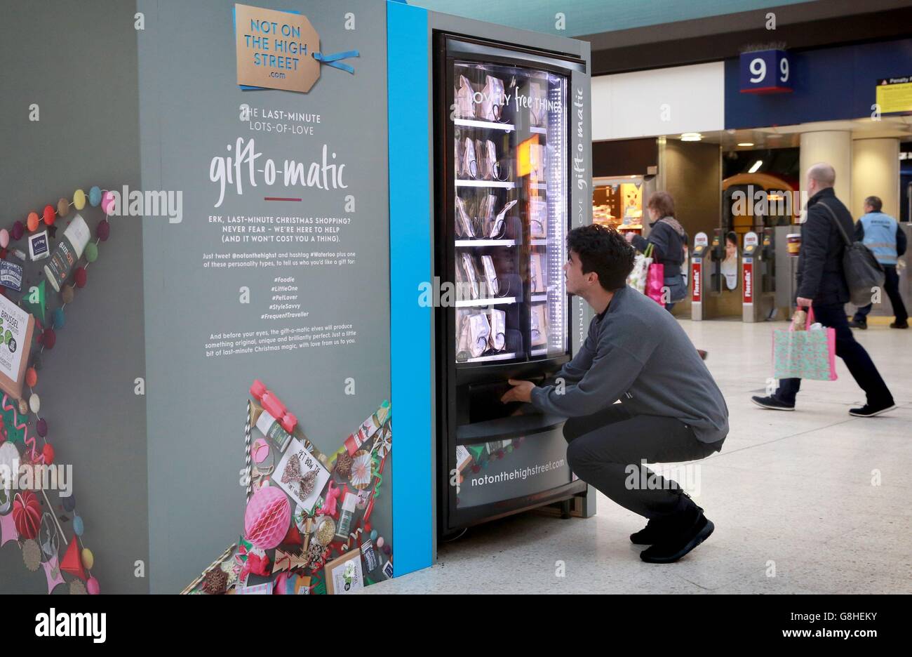 A commuter receives a gift from a 'Gift-O-Matic' machine, which offers free stocking filler gifts from notonthehighstreet.com, to take the stress out of last minute shopping at London Waterloo train station. Stock Photo