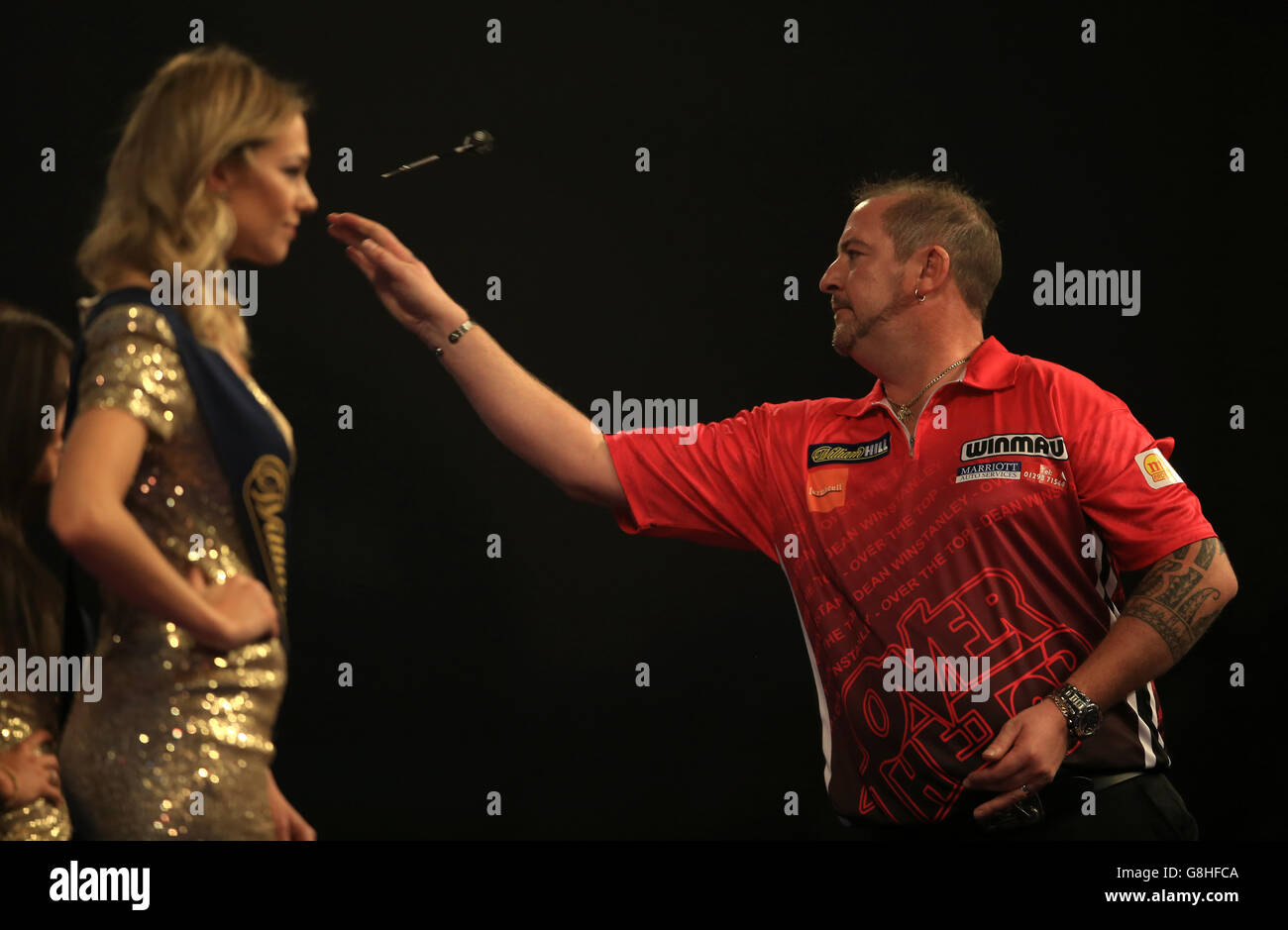 Dean Winstanley during his practice throws as the William Hill walk on girls look on during day six of the William Hill PDC World Championship at Alexandra Palace, London. PRESS ASSOCIATION Photo. Picture date: Tuesday December 22, 2015. See PA story DARTS World. Photo credit should read: John Walton/PA Wire. Use subject to restrictions. . No commercial use. Call +44 (0)1158 447447 for further information. Stock Photo