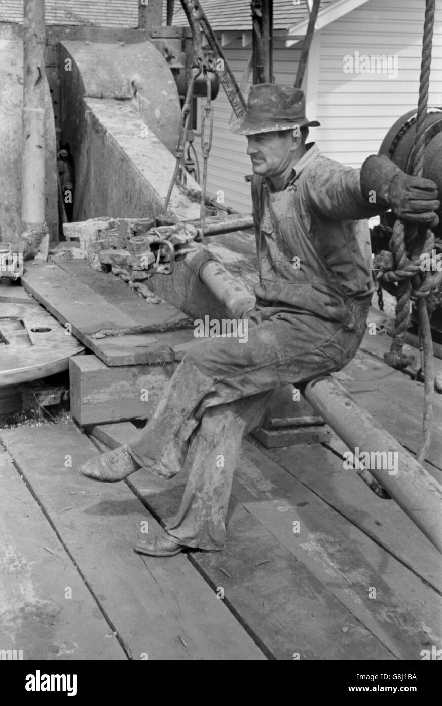 Oil Field Worker Resting on Length of Pipe, Kilgore, Texas, USA