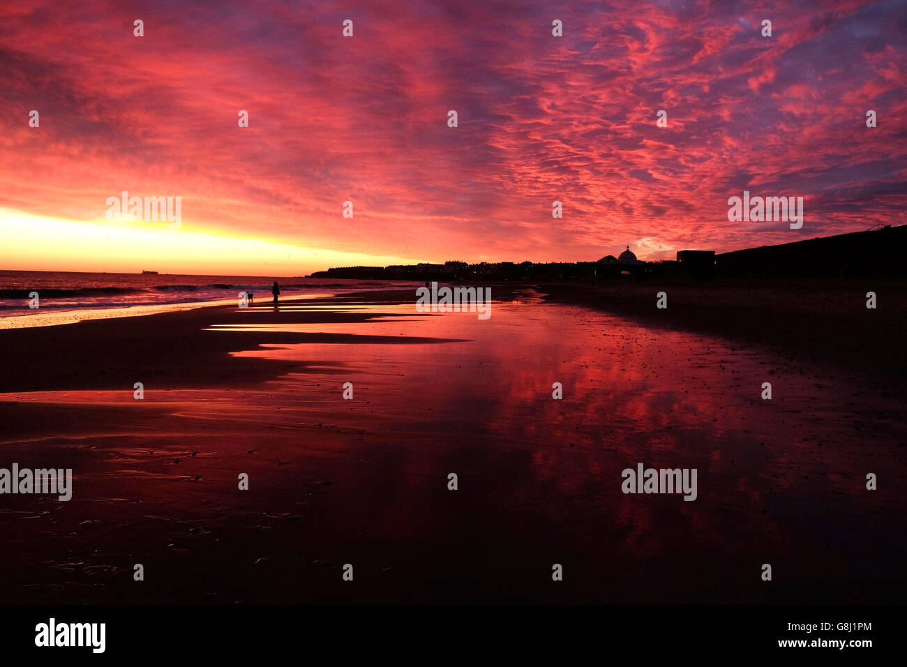 A colourful sky at sunrise on whitley bay beach hires stock