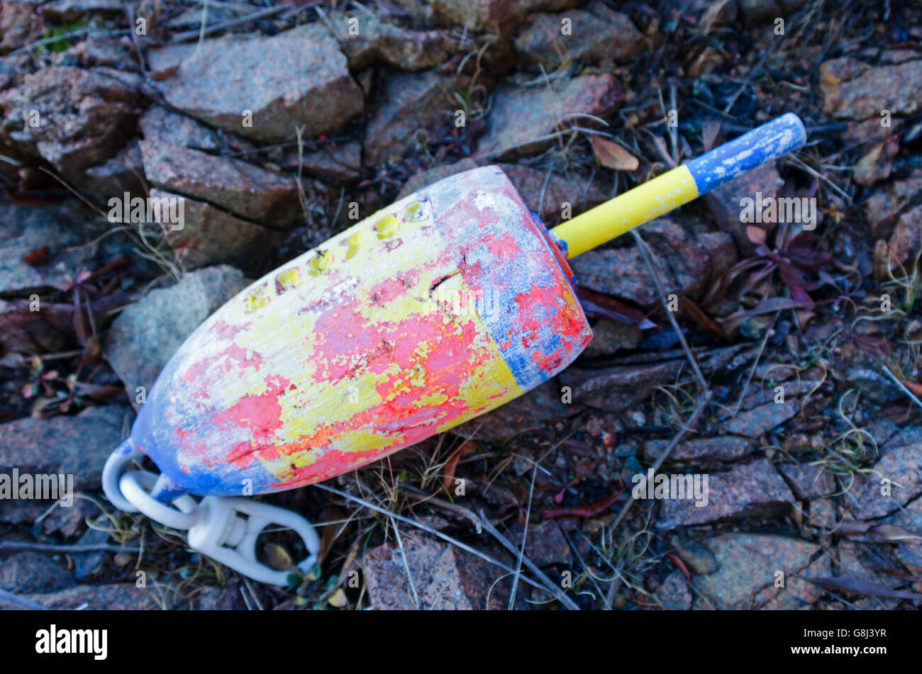 A colorful, weathered lobster trap buoy marker washed up on the shore