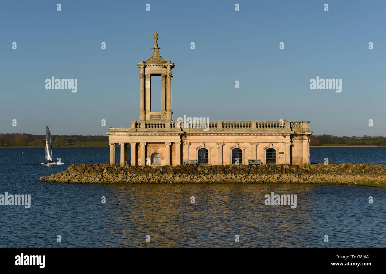 A person in a sailing dinghy passes Normanton Church at Rutland Water reservoir in Rutland Stock