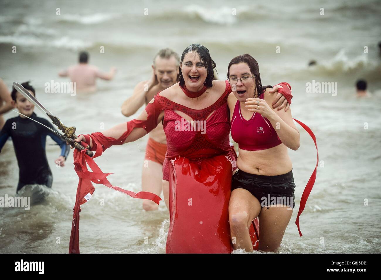 People in fancy dress splash around in the sea at Barry Island, near Cardiff in Wales, where the annual New Year's Day swim is taking place. Stock Photo