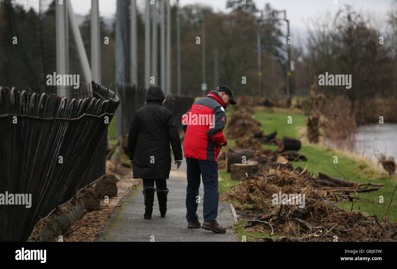 Locals walk along a damaged pathway in Peebles in the Scottish Borders, begin clearing up following Storm Frank, as forecasters issued a fresh warning for more persistent rain over the weekend. Stock Photo