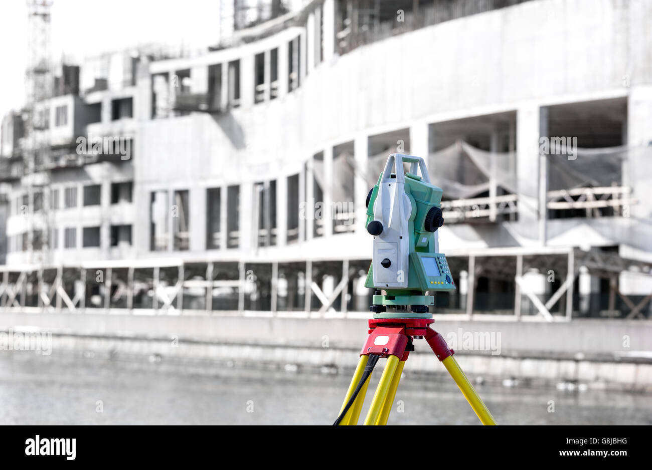 Measurement device (theodolite) mounted on tripod at construction site Stock Photo