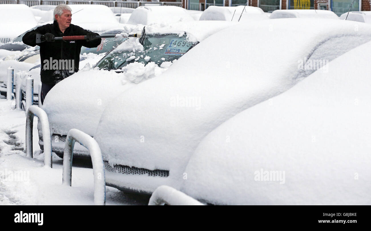 A man clears snow from cars in a garage forecourt after heavy snow at Stanley in Co Durham. Stock Photo