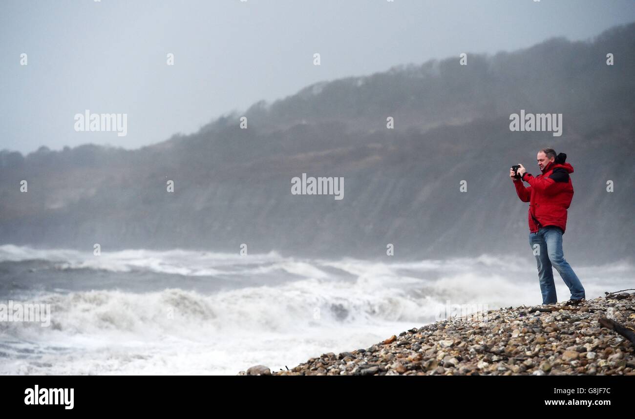 A man takes a photograph at Lyme Regis, Dorset, as Storm Frank begins to batter the UK on its way towards flood-hit areas. Stock Photo