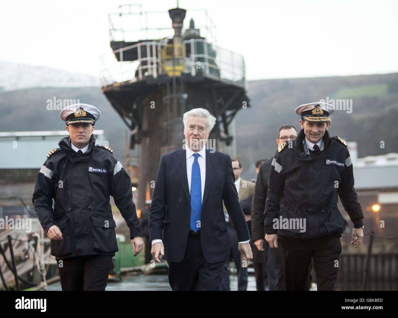 Defence Secretary Michael Fallon (centre) with Daniel Martyn (left) Commanding Officer of HMS Vigilant and Rear Admiral of Submarines and Assistant Chief of Naval Staff John Weale (right) during a visit to Vanguard-class submarine HMS Vigilant, one of the UK's four nuclear warhead-carrying submarines, at HM Naval Base Clyde, also known as Faslane, in Scotland. Stock Photo