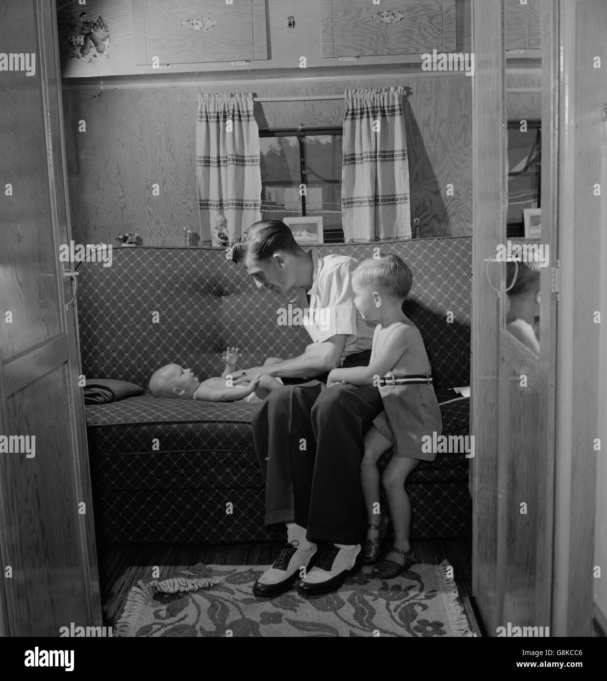 Father with Two Children in Trailer Home at Glenn L. Martin Trailer Village, a Farm Security Administration (FSA) Housing Project, Middle River, Maryland, USA, John Collier for Office of War Information, August 1943 Stock Photo