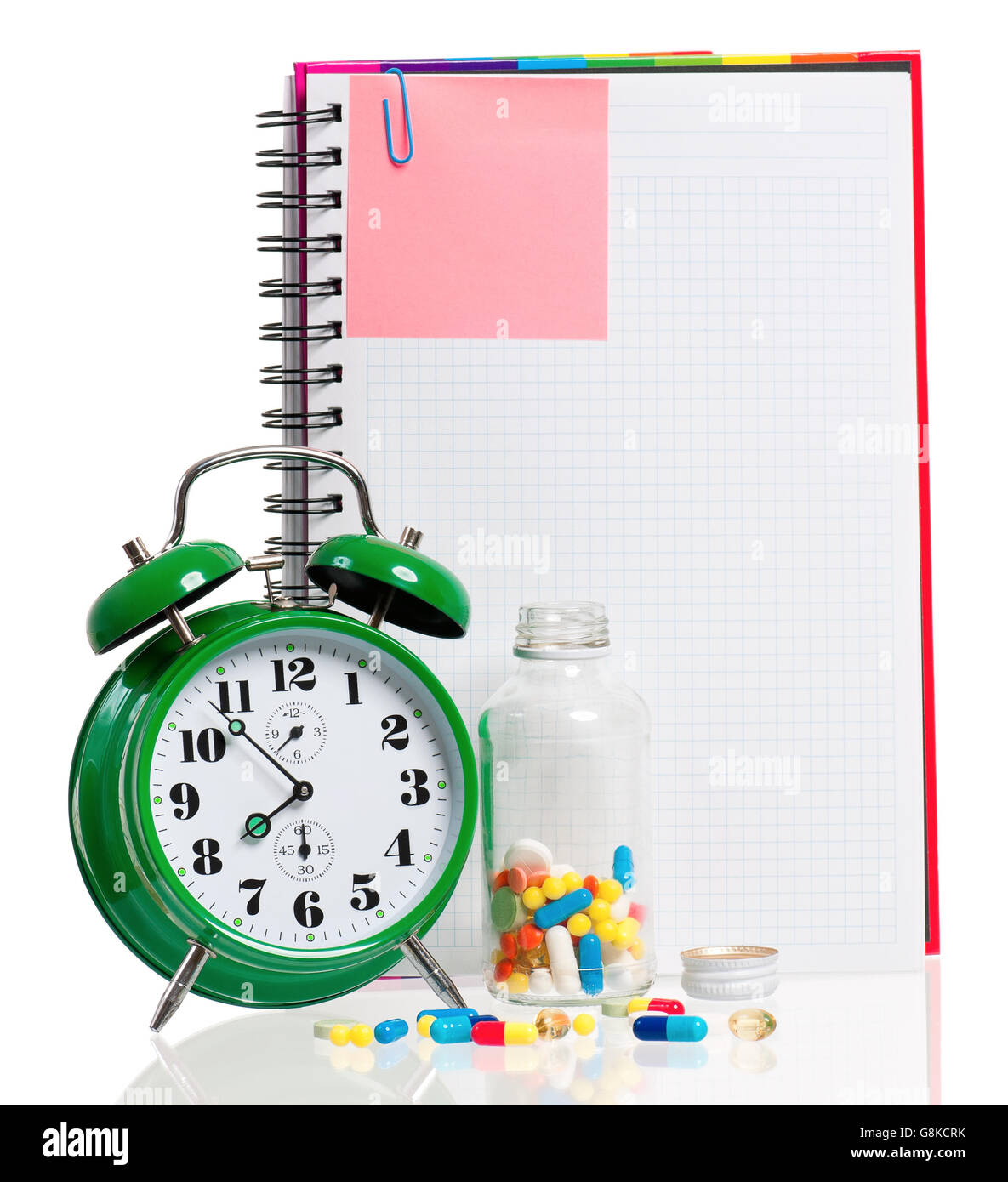 Green alarm clock with pills Stock Photo