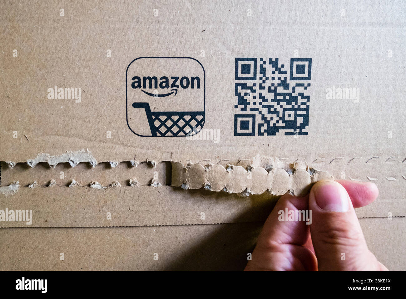 Customer opening a cardboard packet received  from Amazon.com online shop Stock Photo