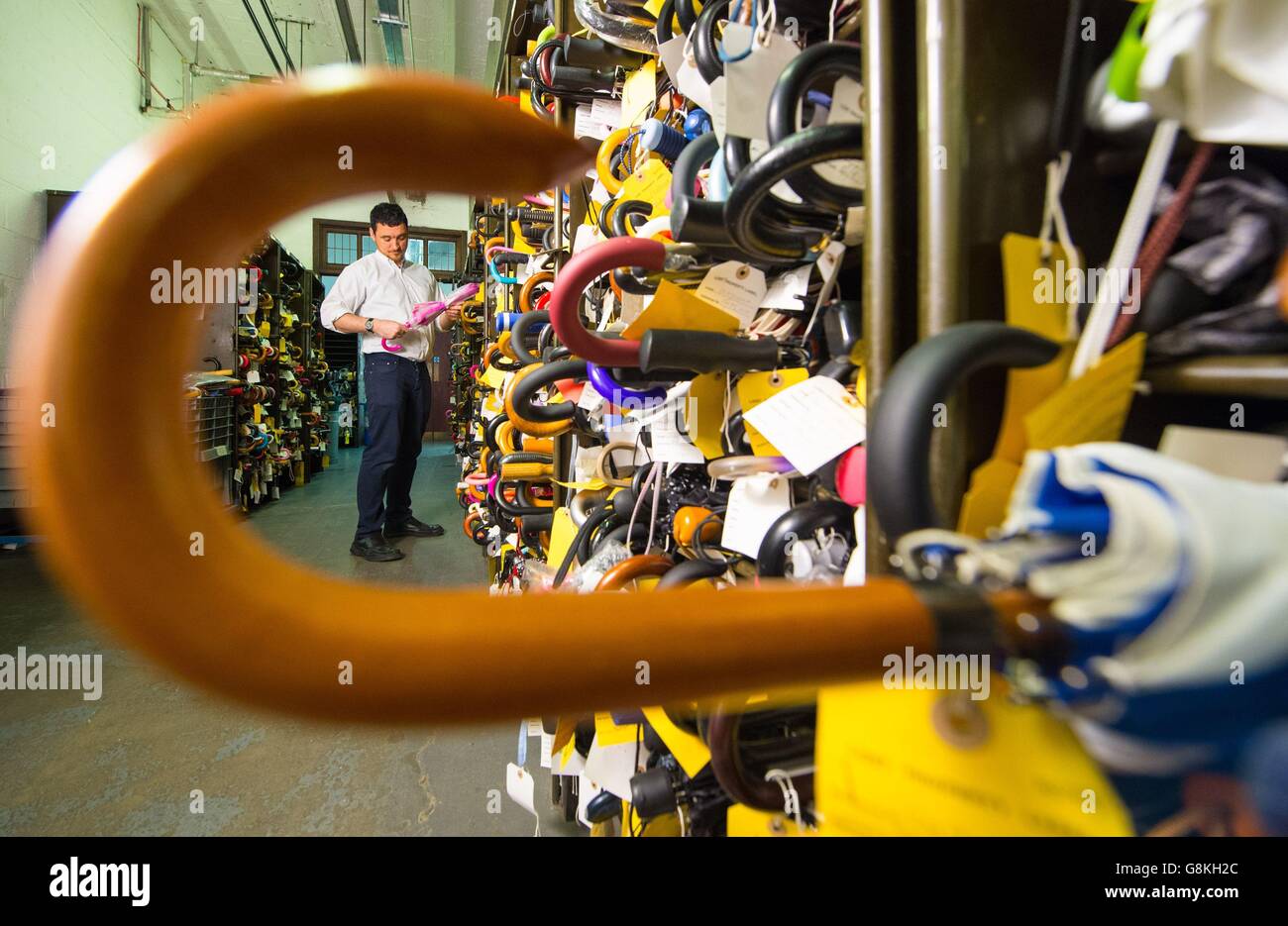 An employee examines one of the thousands of umbrellas are among the items at the Transport for London Lost Property Office, in central London, which sorts and stores the items left on London's public transport system. Stock Photo