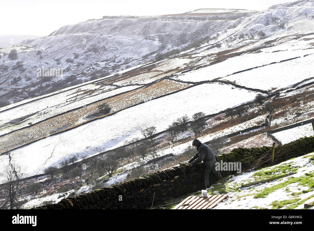 Drystone waller Robert Gregory works on a wall near Buxton in the High Peak District following snowfalls across the area which closed the Snake Pass earlier in the day. Stock Photo