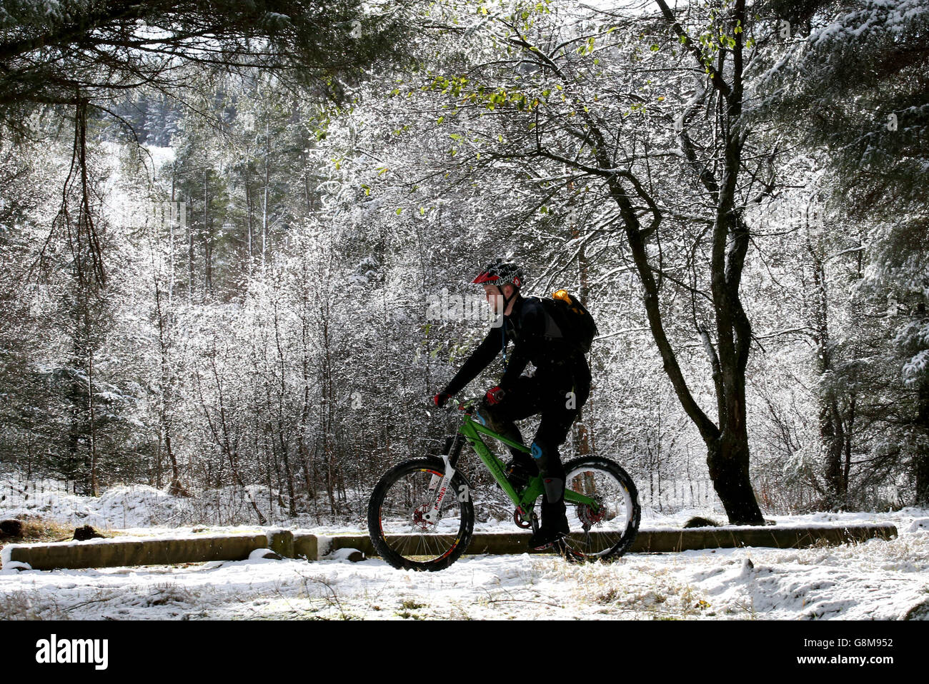 A cyclist rides along the Carron Valley Mountain Bike Trail in Stirling, Scotland, as snow, ice and sub-zero temperatures sweep the country. Stock Photo