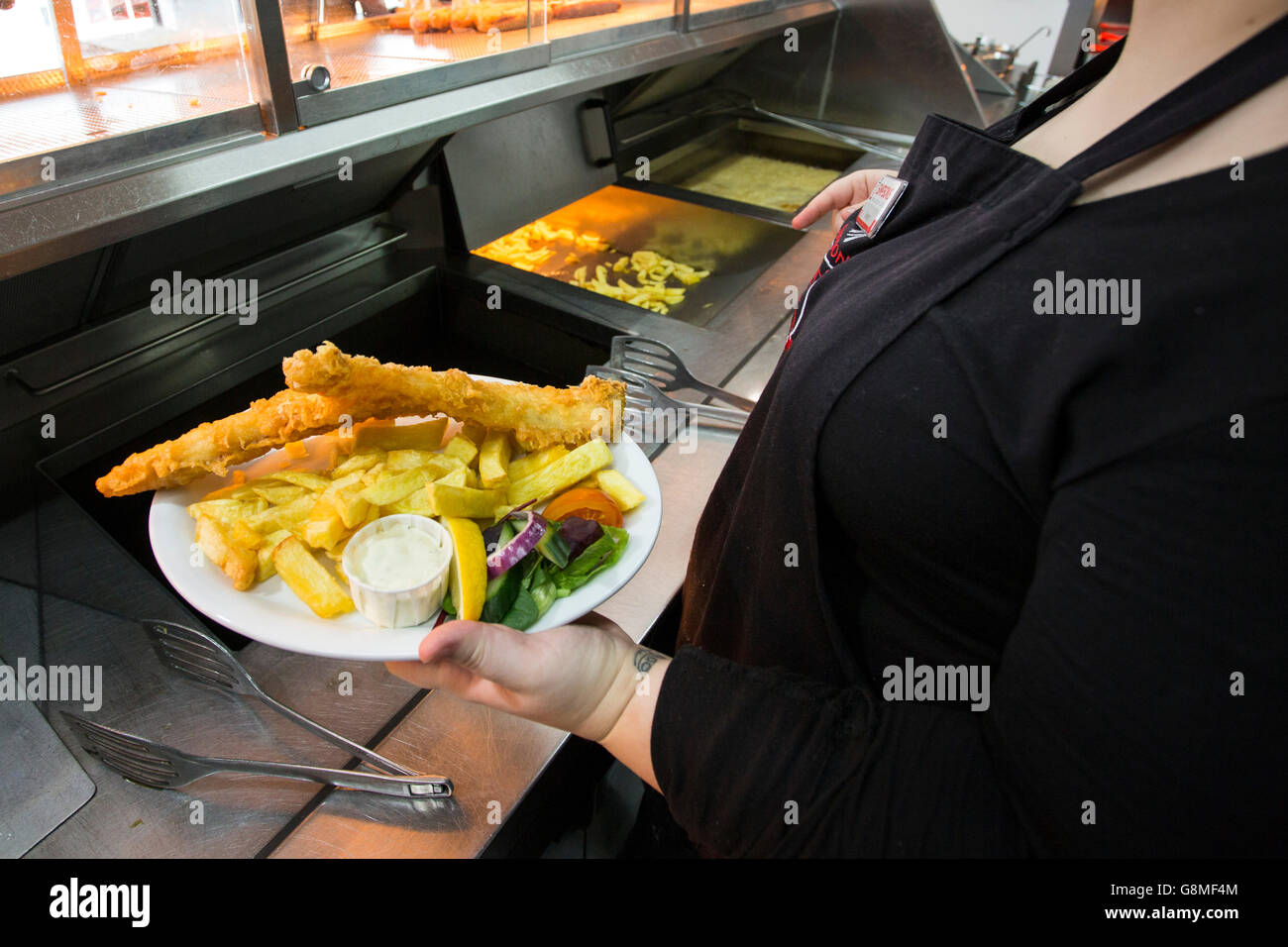 Plates of freshly cooked fish adn chips being served in a posh fish adn