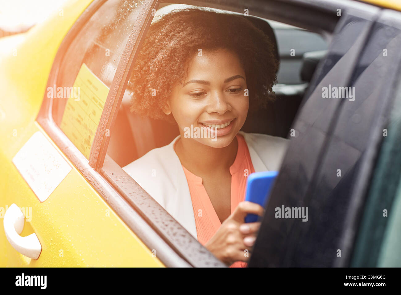 happy african woman texing on smartphone in taxi Stock Photo