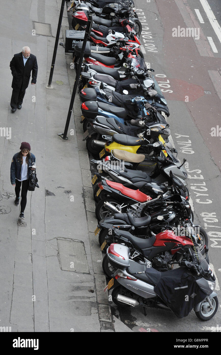 Parking stock. People walk past a motorcycle parking bay on Farringdon