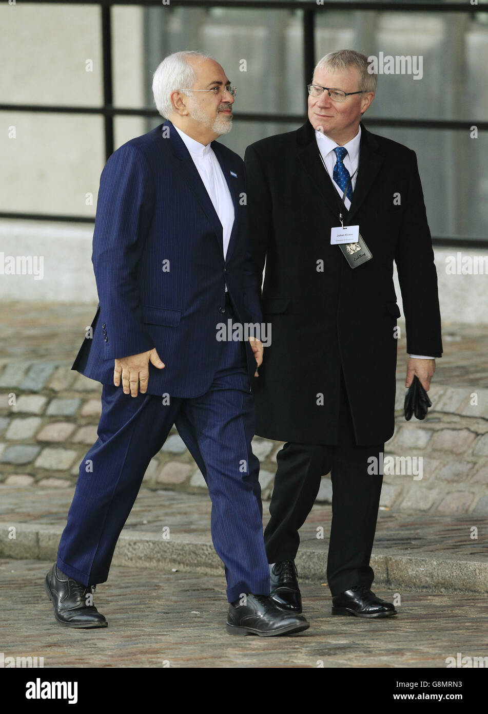 Iranian Foreign Minister Mohammad Javad Zarif (left) is welcomed by Julian Evans, Director of Protocol at the Foreign and Commonwealth Office, as he arrives at the Queen Elizabeth II Conference Centre in London where world leaders are gathering for talks over the Syrian refugee crisis. Stock Photo