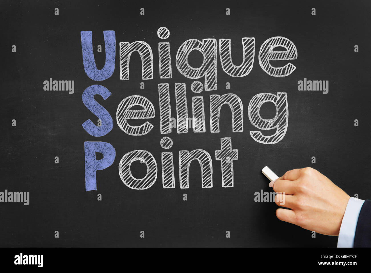 Hand writes 'Unique Selling Point' on blackboard Stock Photo