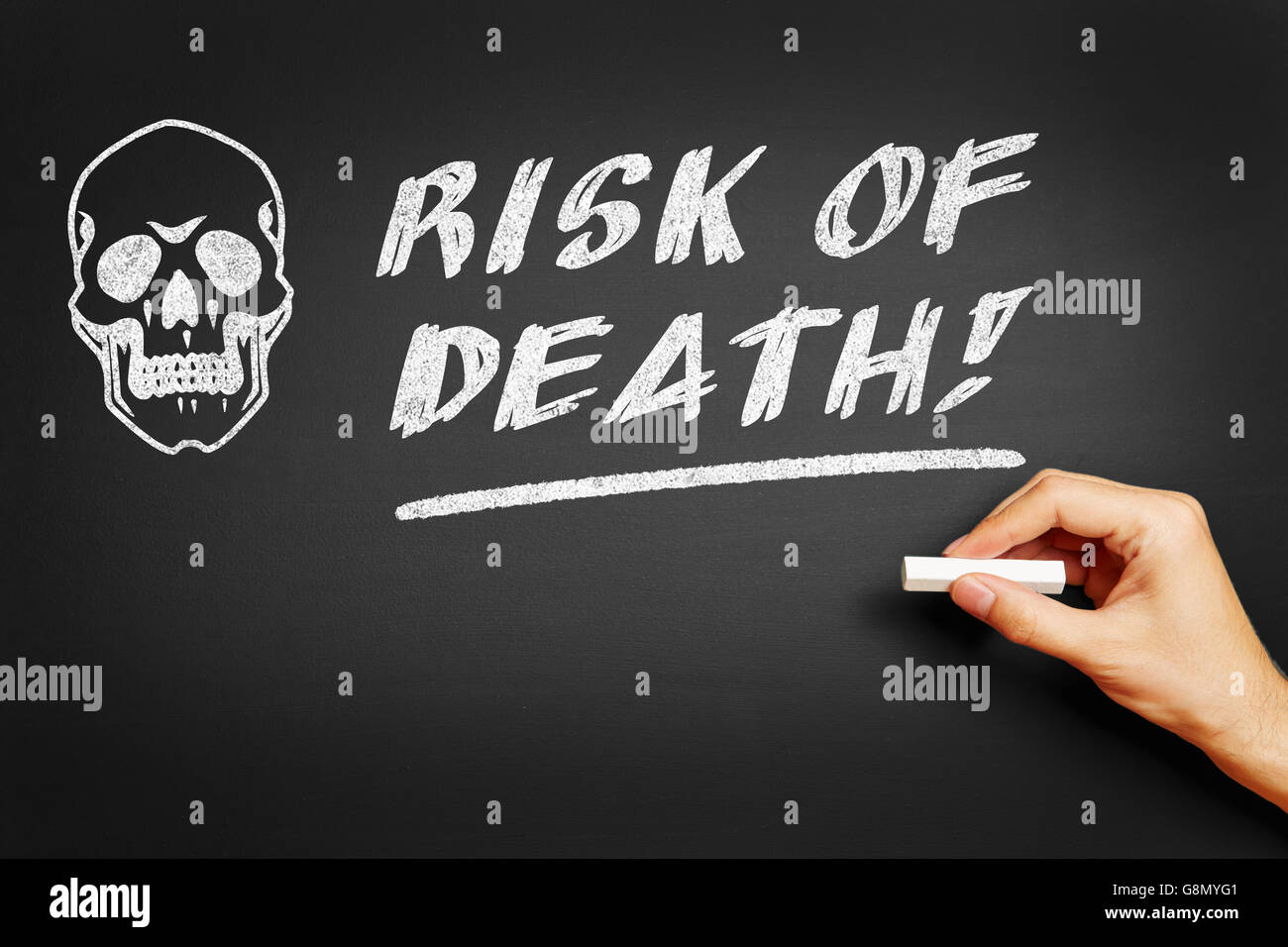 Hand with chalk writing 'Risk of death!' on a blackboard Stock Photo