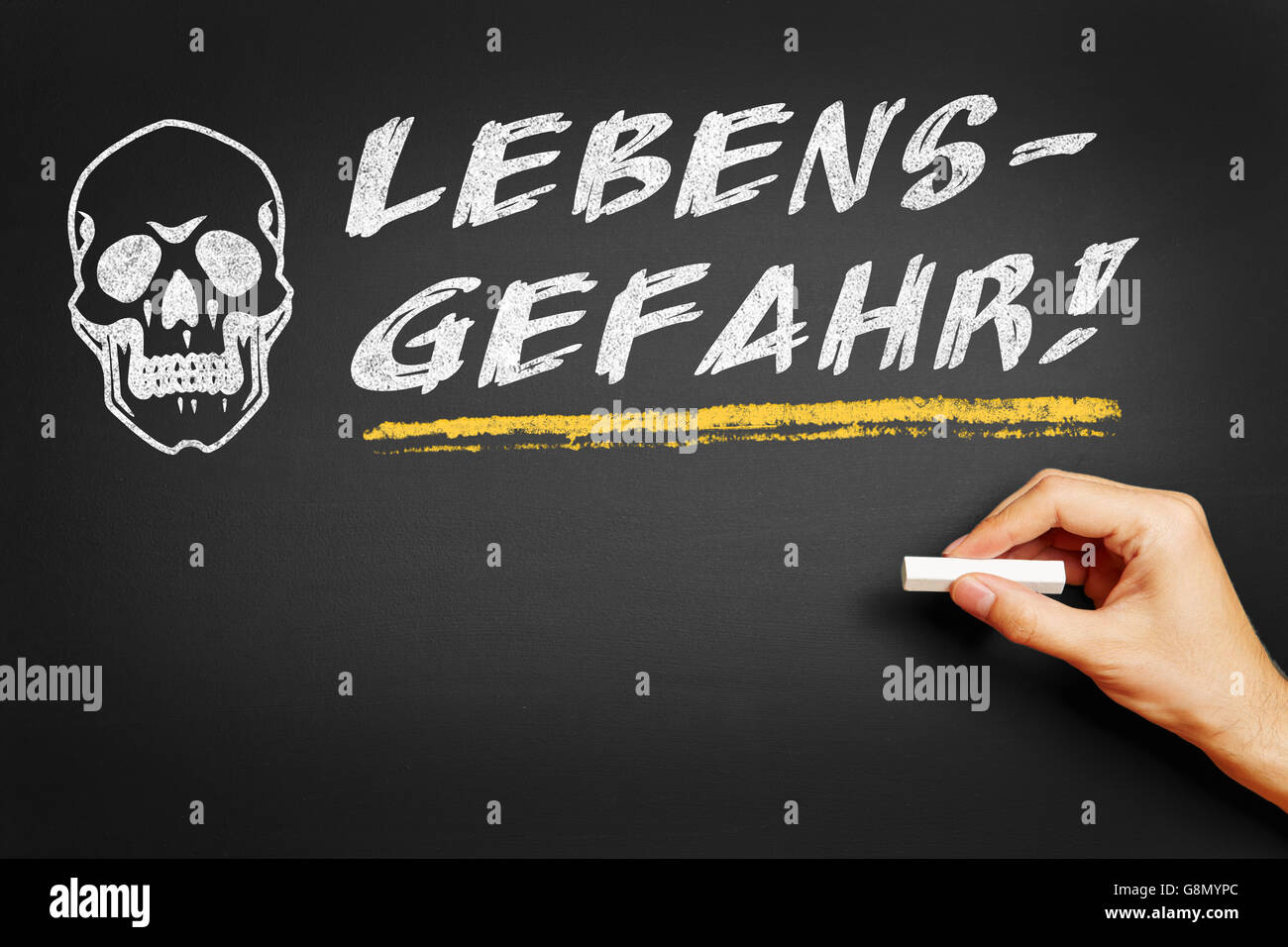 Hand with chalk writing in German 'Lebensgefahr!' (Mortal danger) on a blackboard Stock Photo