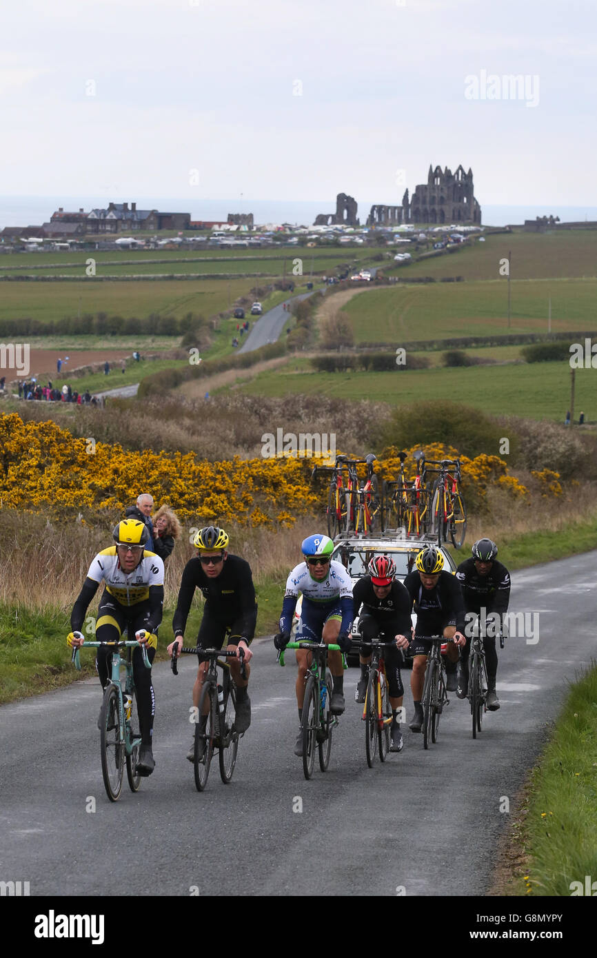 The peloton, with the famous abbey behind them, makes it's way out of Whitby in the final stage of the Tour de Yorkshire. Stock Photo