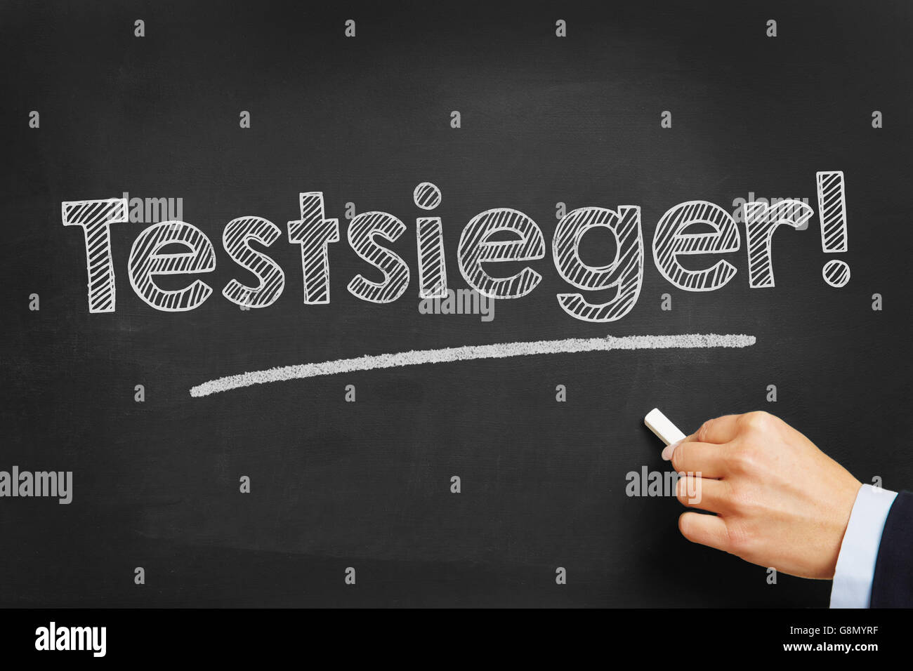 Hand with chalk writing in German 'Testsieger!' (Best in test) on a chalkboard Stock Photo