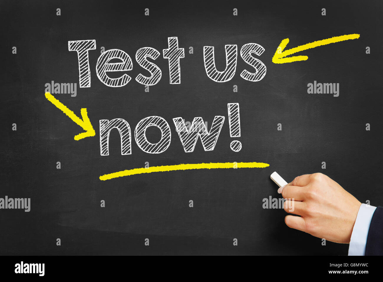 Hand writing with chalk 'Test us now!' on a blackboard Stock Photo