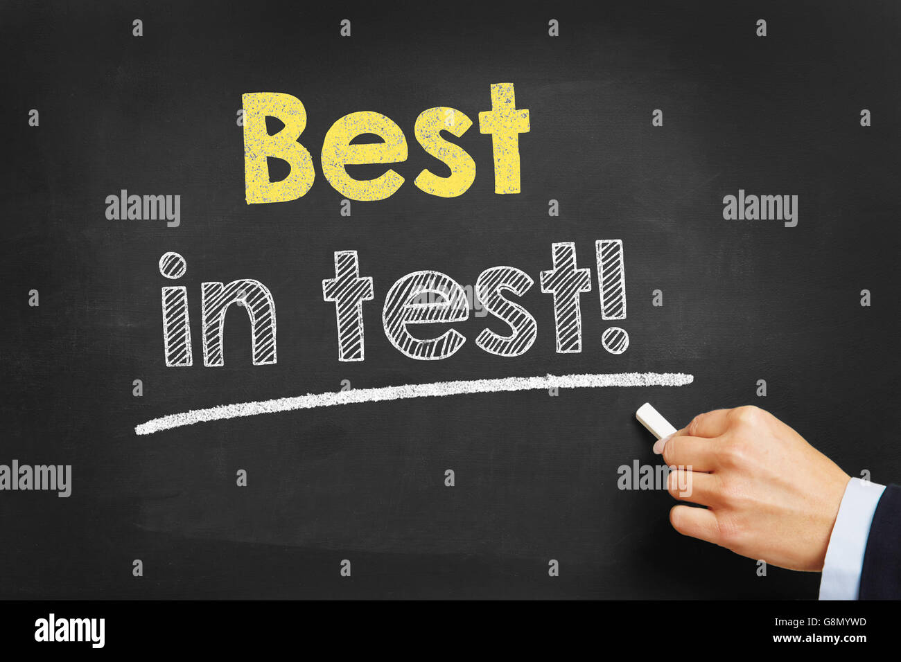 Hand with chalk writing 'Best in test!' on a blackboard Stock Photo