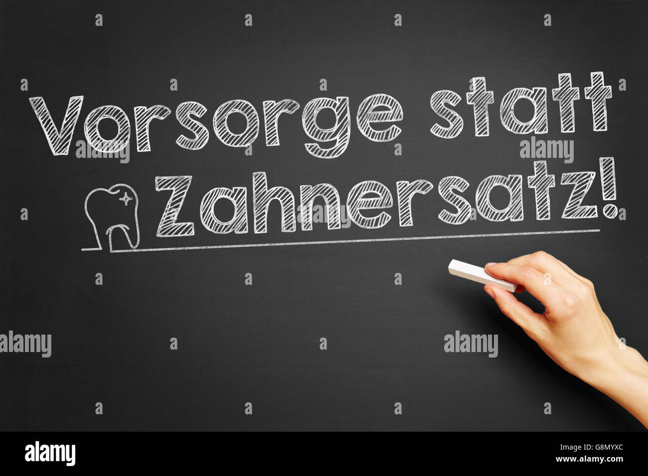 Hand writes in German 'Vorsorge statt Zahnersatz!' (Precaution instead of dental prosthesis) on blackboard Stock Photo