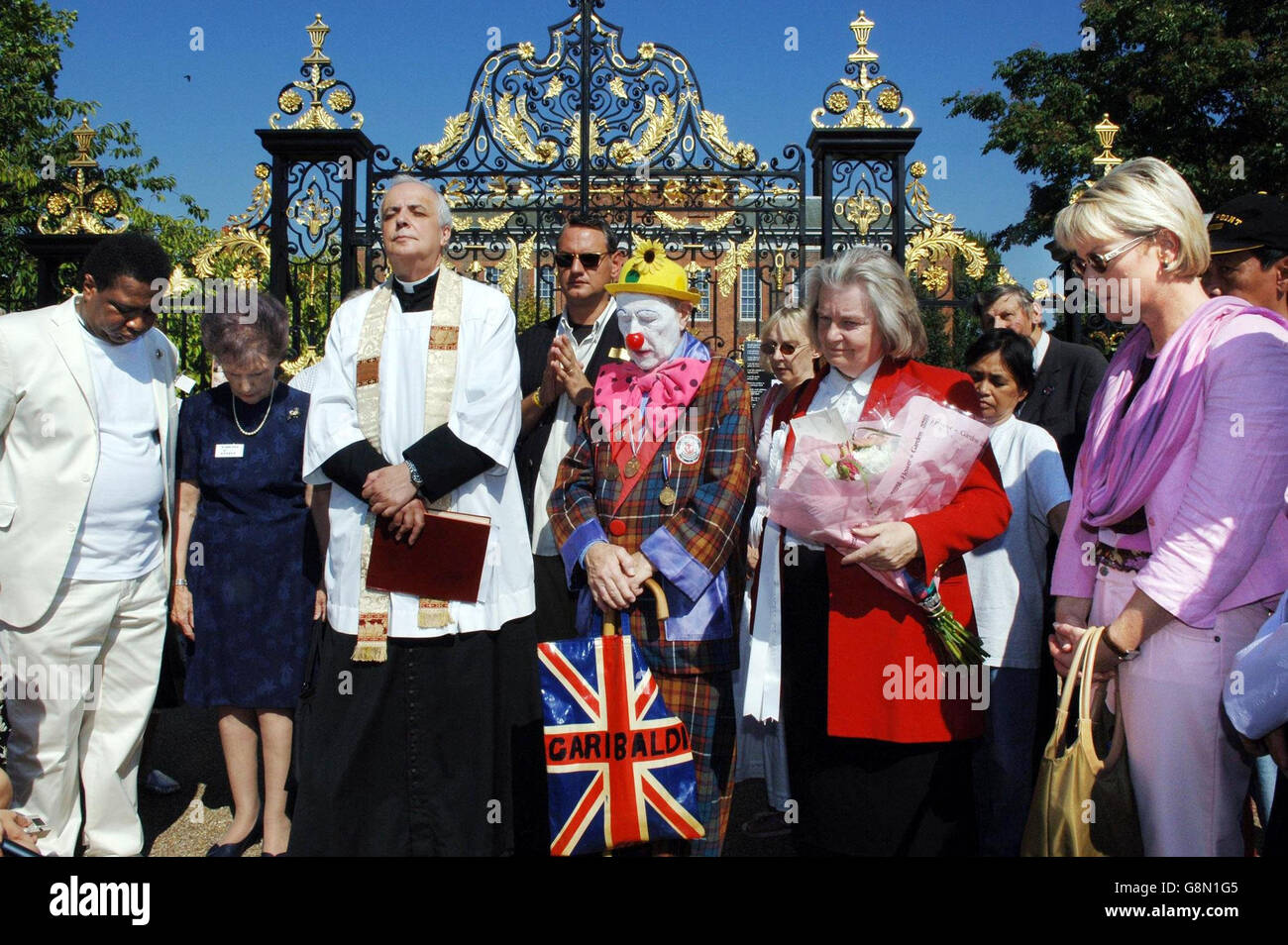 Fans of Diana, Princess of Wales share a minutes silence outside Kensington Palace with Father Frank Gelli, the former curate of nearby St Mary Abbots Church, Wednesday August 31, 2005. Tributes in memory of the Princess were tied to the gates of Kensington Palace today to mark the eighth anniversary of her death. See PA story ROYAL Diana. PRESS ASSOCIATION photo. Photo credit should read: Fiona Hanson/PA. Stock Photo