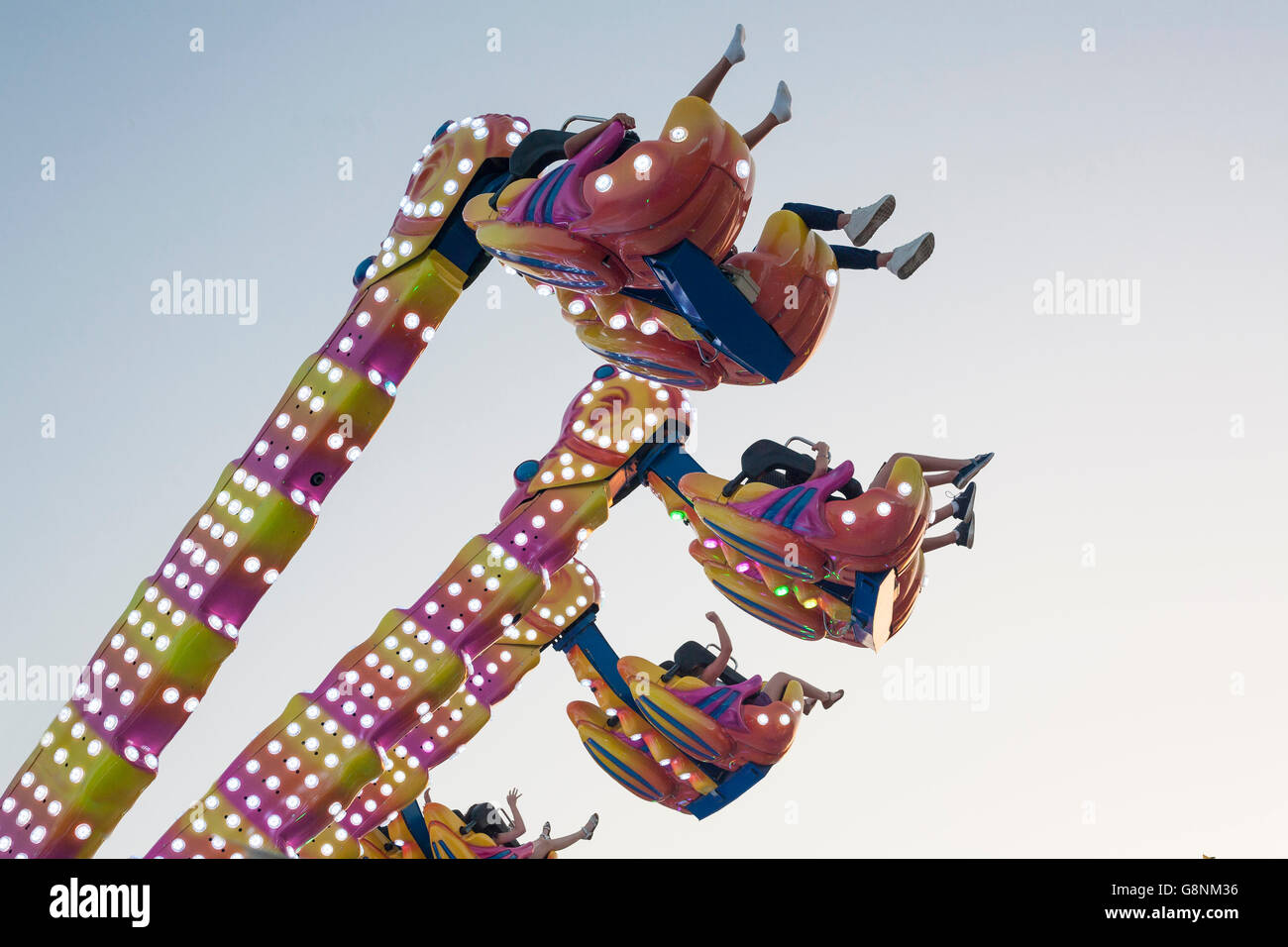 Hanging funfair attraction with people having fun. low angle view Stock Photo