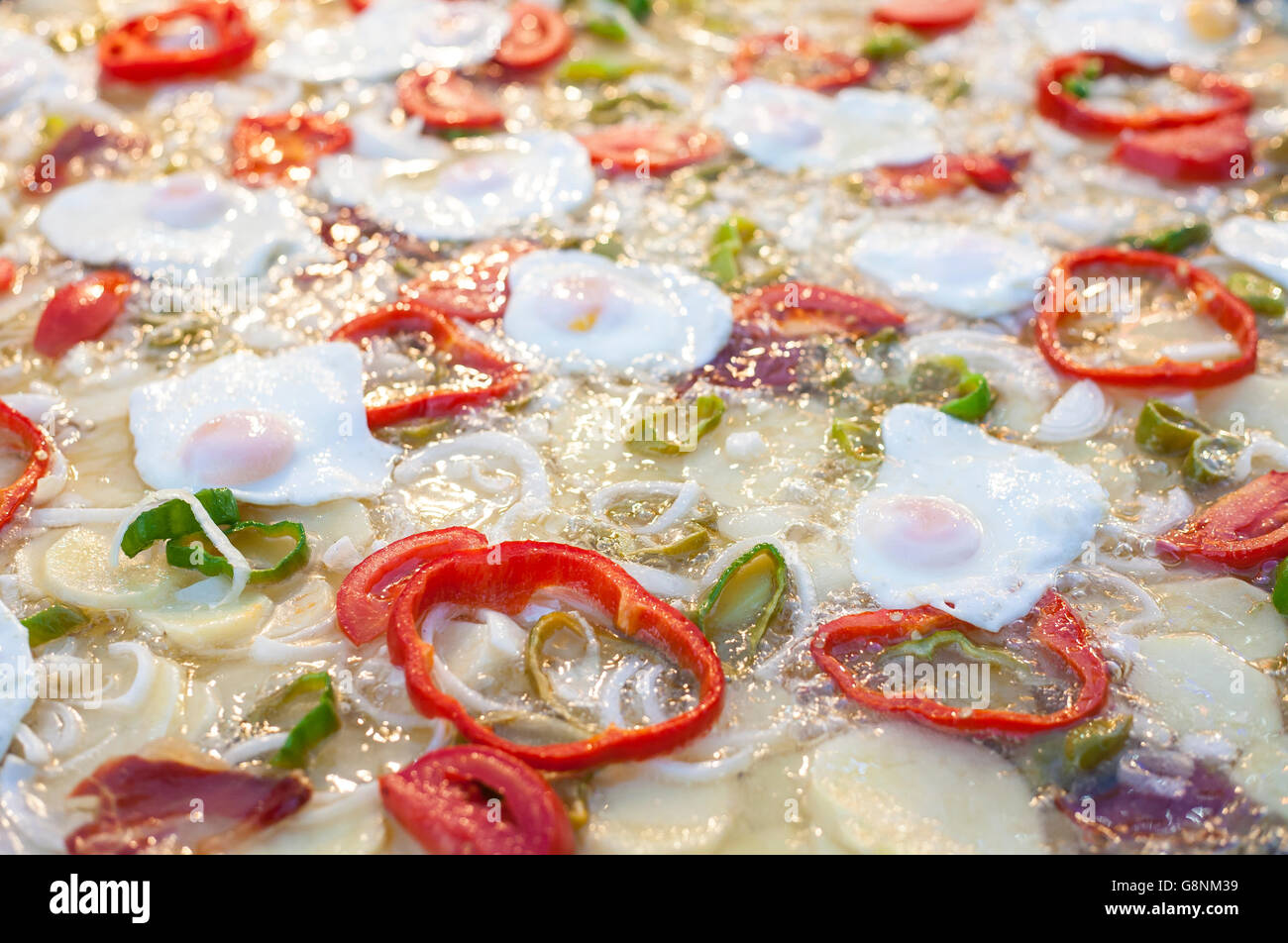 Boiling huge pan with eggs, pepper slices, potatoes and onions Stock
