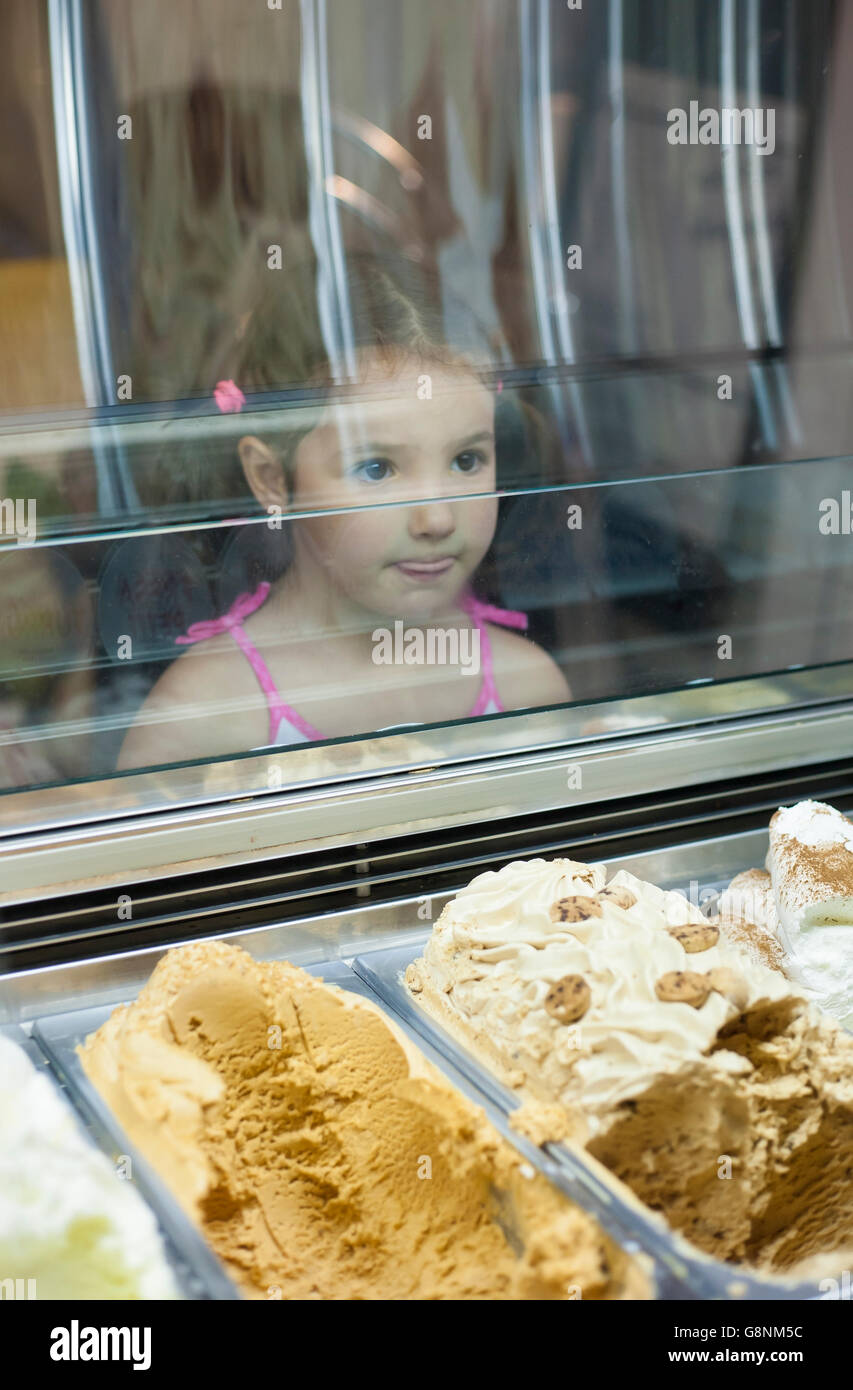 Little girl wishes ice cream in pastry shop. Reflections on ice cream