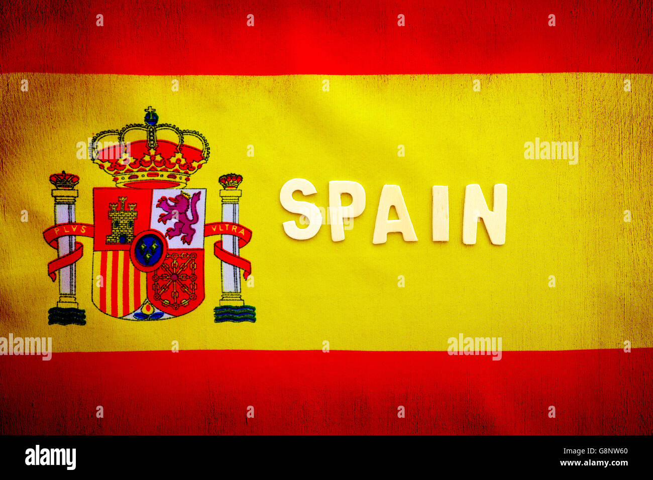 Spanish flag, yellow and red cloth with national Spain emblem, text space, grunge style patriotic wallpaper Stock Photo