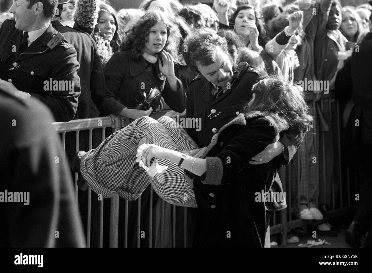 A young girl who fainted is carried from a crowd of screaming teenagers by a policeman as youngsters besiege the Rainbow Theatre in Finsbury Park, London. The teens are hoping to buy tickets for The Osmonds concert in October. All the tickets had been sold. Stock Photo