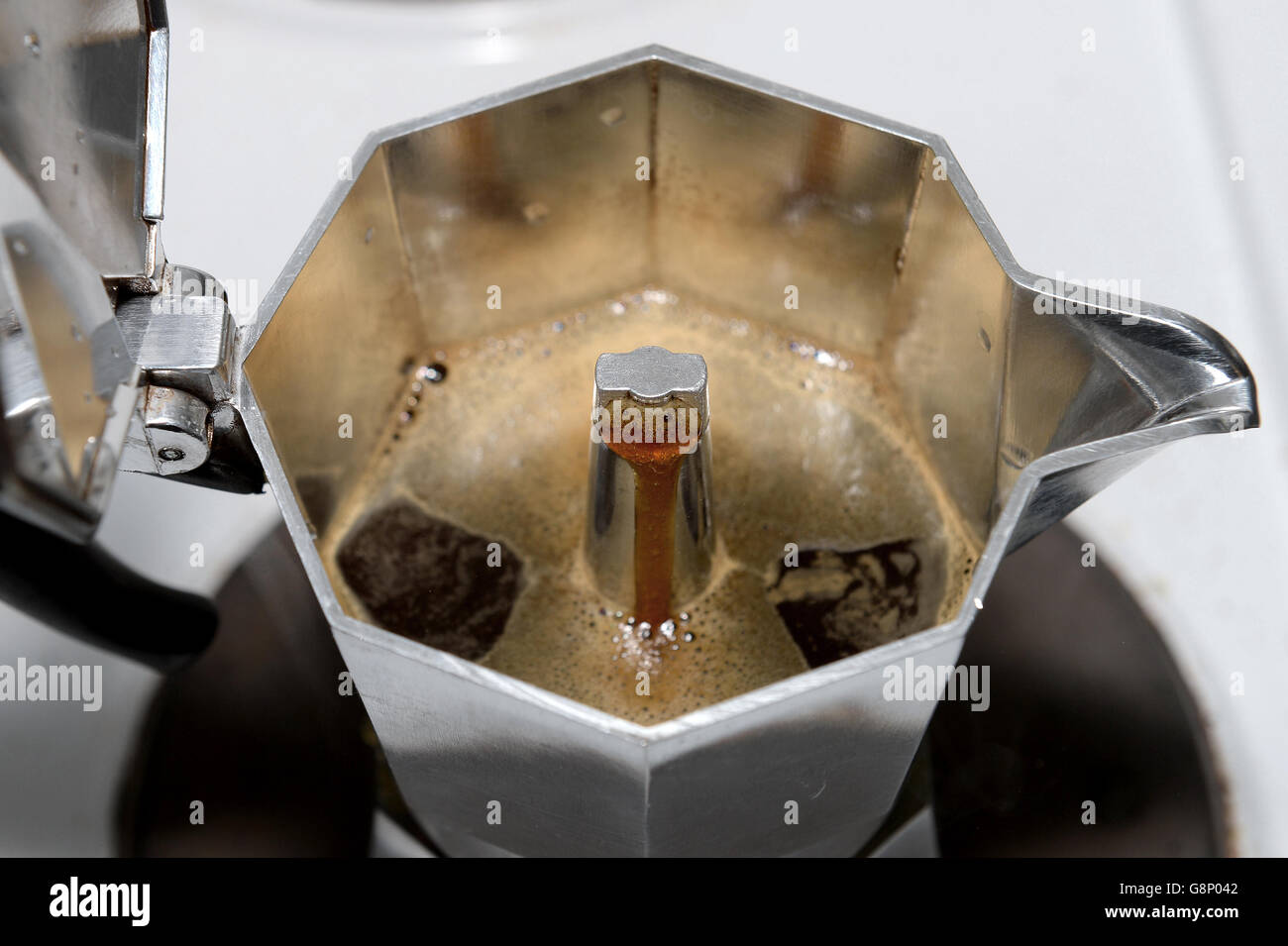 Coffee perculates through a stovetop espresso coffee maker on an