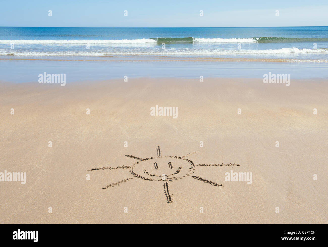 Smiley face sun drawing on a beach. UK Stock Photo