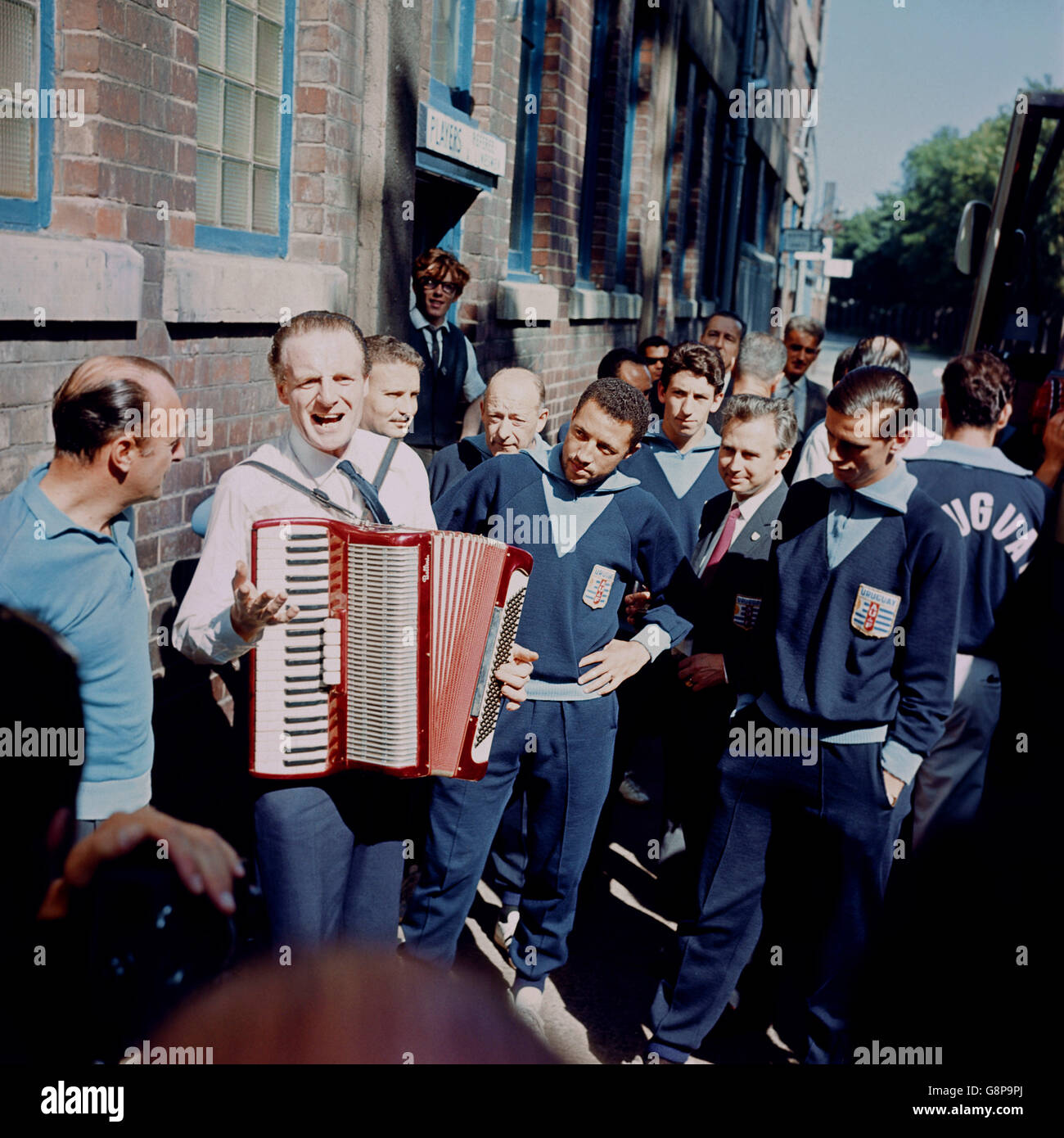 Soccer - World Cup England 1966 - Uruguay Training - Hillsborough. Uruguay's Julio Cortes (c) and Luis Ramos (r) are intrigued by a local accordion player as they wait to board the team coach Stock Photo