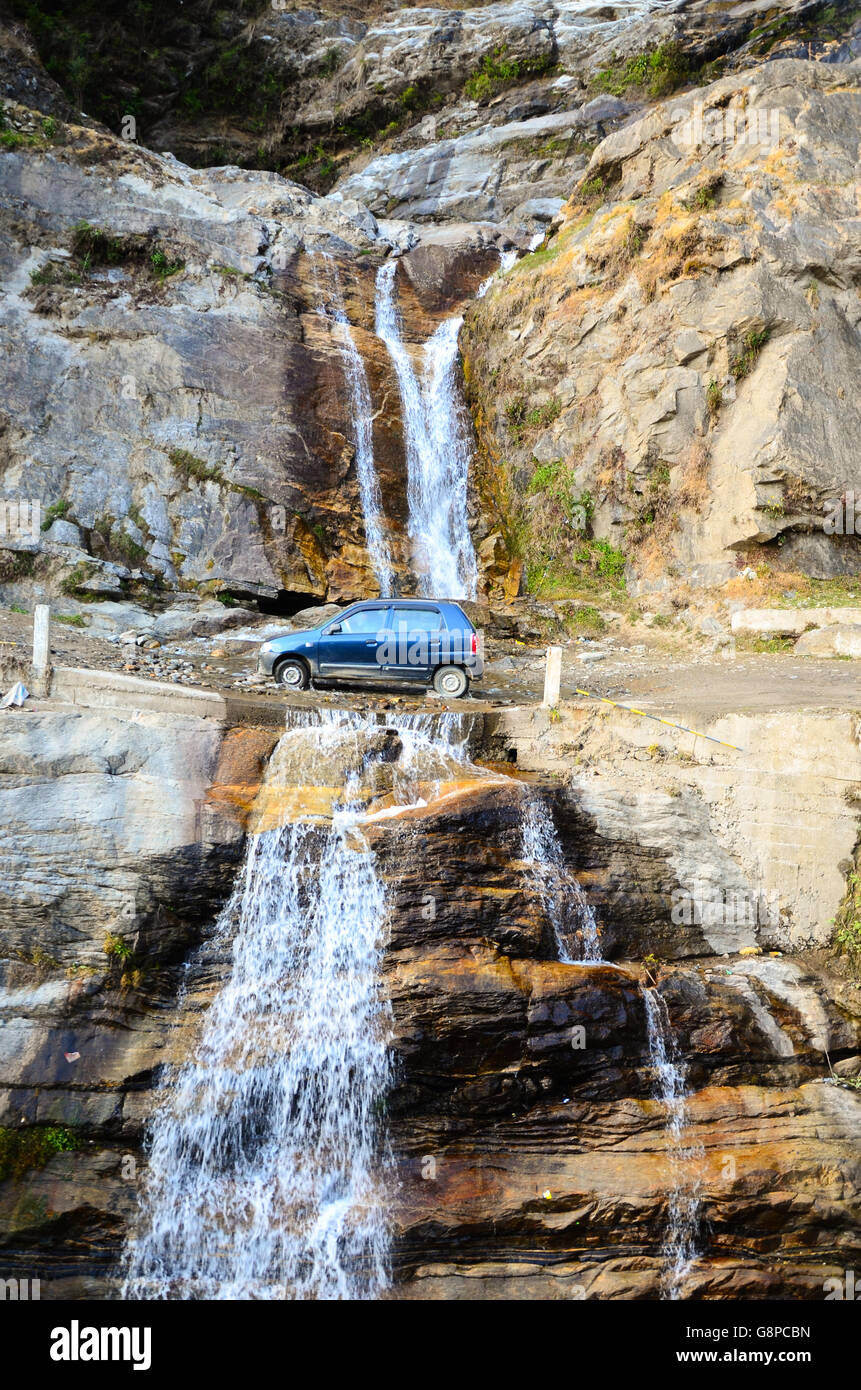 Maruti Suzuki Alto car on a road through waterfall on the way to Singshore Suspension Bridge in Pelling, Sikkim, India Stock Photo