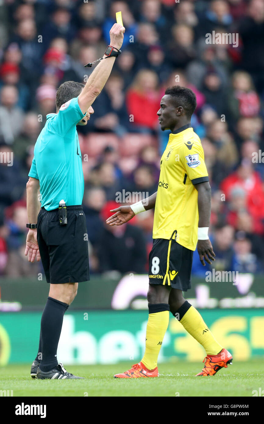 Stoke v Aston Villa - Barclays Premier League - Britannia Stadium. Match referee Kevin Friend gives a yellow card to Aston Villa's Idrissa Gueye Stock Photo