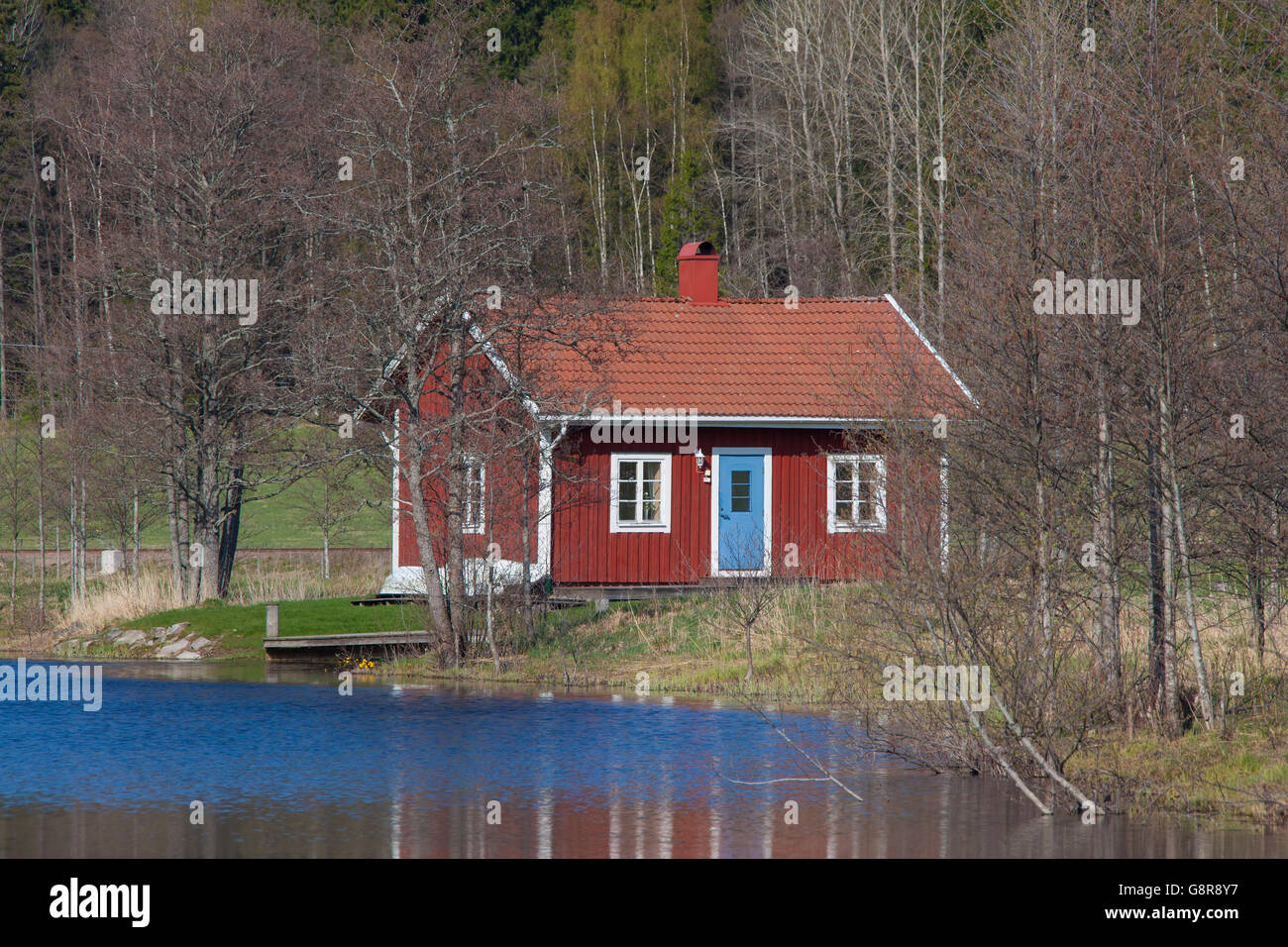 Swedish red wooden cabin along river in spring, Värmland, Sweden Stock Photo
