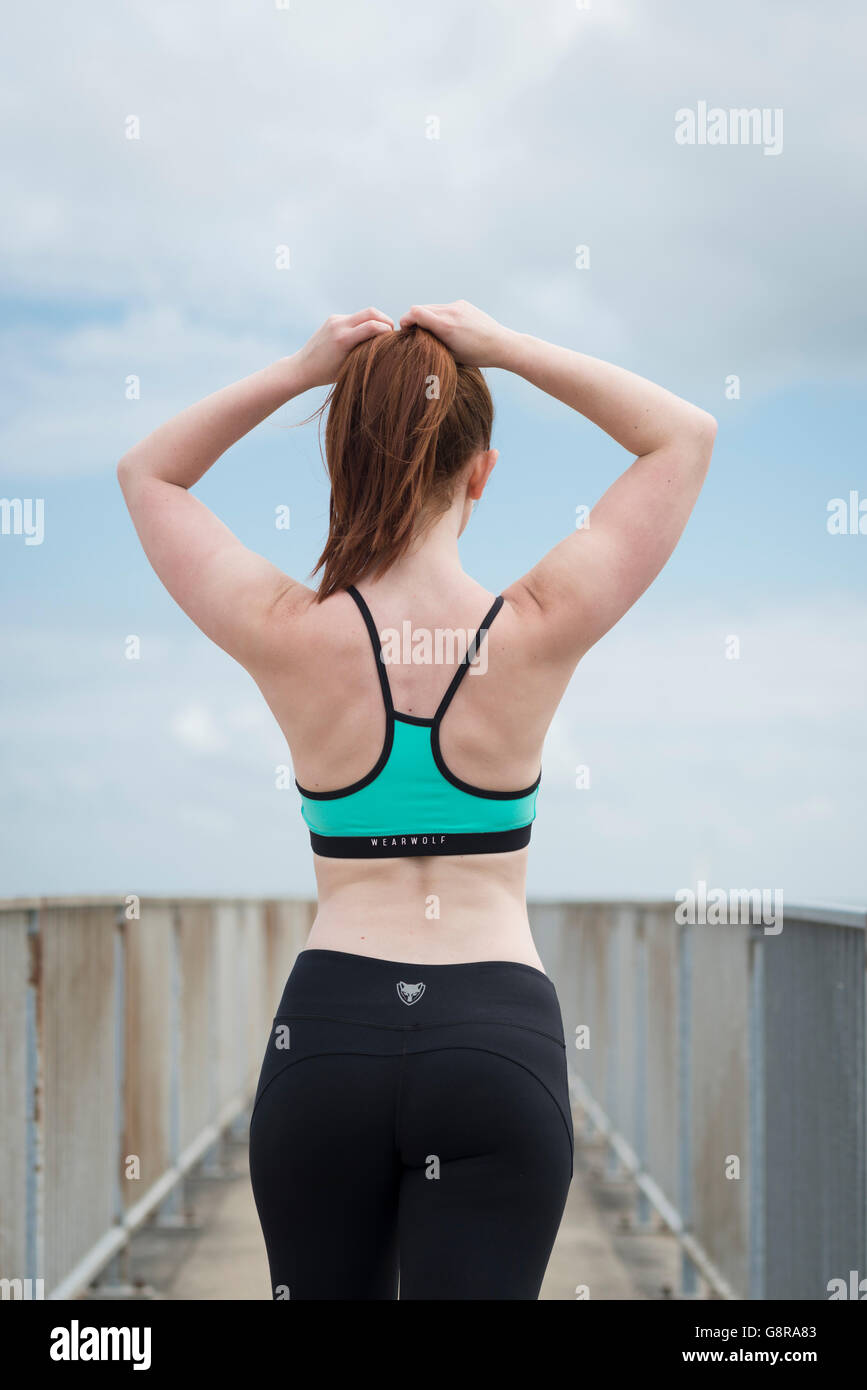 woman wearing fitness wear adjusting her hair viewed from behind Stock Photo